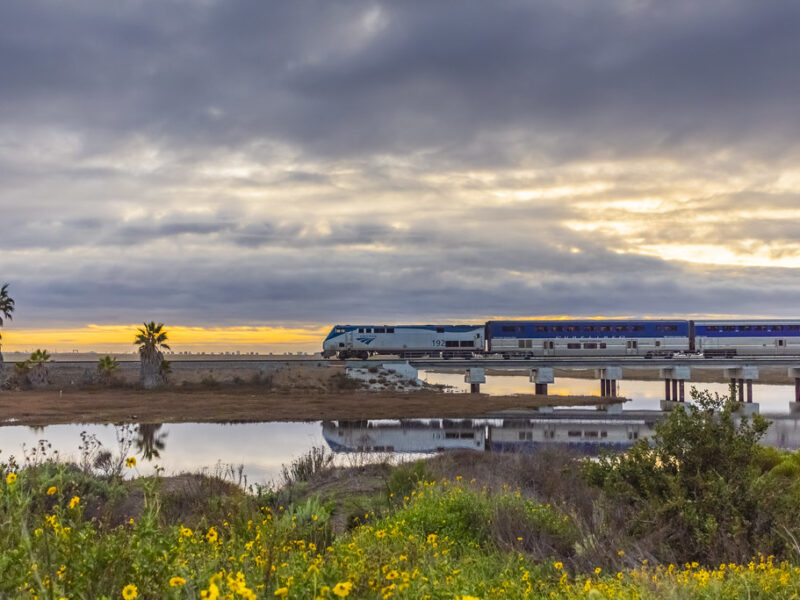 Amtrak Pacific Surfliner train heading south near Torrey Pines State Beach at sunset